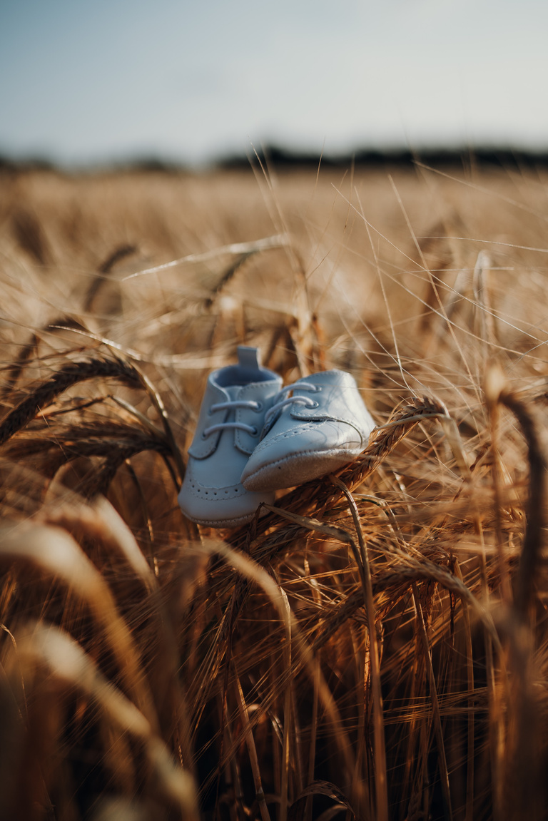 Baby shoes balanced on wheat in field. 

Midwife Kaleigh supports home birth, water birth, and out of hospital Midwifery care. She believes pregnancy is not an emergency and provides Midwifery care in your home. 